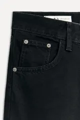 Pantalón de jean negro de corte ancho, tiro alto, con cinco bolsillos y cierre frontal con cremallera y botón metálico.