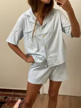 Conjunto de pijama celeste a rayas verticales, compuesto por una camisa de manga corta con botones y un short.