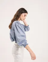 Blusa celeste de cuello mao y mangas abullonadas con puños elásticos. Tiene tajos laterales y botones en la delantera.