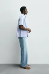 Camisa de manga corta color verde grisáceo, de corte regular fit, confeccionada en tejido suave y elástico con cierre de botonadura frontal.