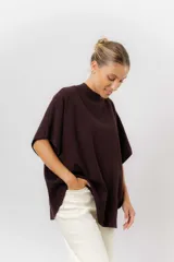 Sweater de tejido de punto color negro, con cuello semi alto y mangas cortas amplias. Presenta una silueta relajada y caída fluida.