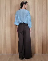 Pantalón de jean color beige, de corte recto y tiro alto, con ruedo deshilachado y cierre frontal con botón y cremallera.