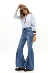 Pantalón de denim color marrón con corte acampanado y diseño de paneles en el ruedo que aporta volumen y movimiento.