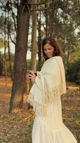 Bufanda de gran tamaño confeccionada en lana merino, con diseño de doble tejido y terminación con flecos largos en los extremos.