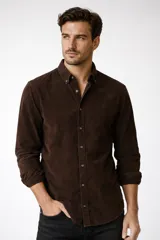 Camisa de pana color marrón, de manga larga, con cuello clásico abotonado y cierre frontal con botones.