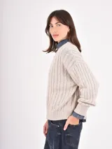 Buzo de tejido de punto con diseño de trenzas verticales, cuello redondo, mangas largas y puños acanalados.