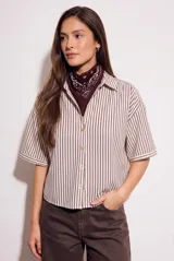 Camisa de corte oversize con estampado de rayas verticales en tonos marrón y beige. Presenta cuello camisero, cierre frontal con botones y mangas cortas con caída relajada.