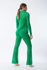 Camisa de encaje color verde, con cuello clásico, cierre frontal de botones y mangas largas. Presenta un diseño ajustado y texturizado con motivos florales.