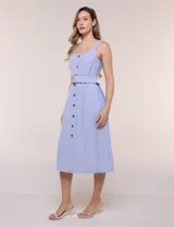 Vestido midi abotonado verde melange, con escote recto, tirantes anchos y falda de calce recto con vuelo sutil. Tiene abotonadura frontal completa con botones estilo carey, cinto textil con hebilla para ajustar la cintura y bolsillos laterales.