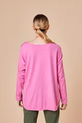 Remera color verde oliva, de algodón italiana con frente de satén, corte holgado, mangas largas y tajos a los costados. Incluye un colgante con cordón marrón y dije circular con diseño calado.