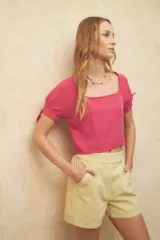 Top corto color blanco roto, con escote cuadrado, manga corta abullonada con lazos ajustables en el borde y textura arrugada en el tejido.