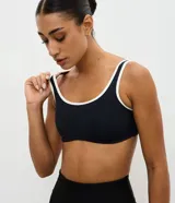 Top deportivo de microfibra con diseño de escote redondo y breteles anchos con ribetes en contraste. Cuenta con copas desmontables y espalda con escote en V.