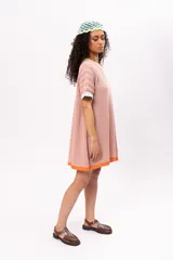 Vestido corto tejido de punto color salmón, con cuello redondo y mangas cortas. Presenta ribetes en color amarillo en el cuello, celeste en las mangas y naranja en el ruedo.