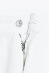 Pantalón blanco de jean con bordados calados en los laterales, de tiro medio y pierna ancha.