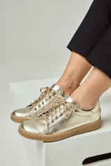 Zapatillas de cuero color dorado con acabado metalizado, cordones al tono y suela de goma color suela.
