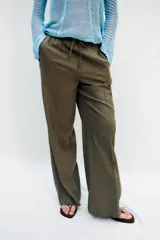 Pantalón recto de lino color verde militar, de tiro medio con cintura elástica ajustable mediante cordón y bolsillos delanteros.