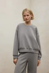 Buzo de cuello redondo, manga larga con puños elásticos y ruedo con banda elástica. Presenta un diseño minimalista y holgado.