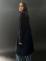 Tapado largo gris de lana merino con bolsillos laterales y corte particular en los hombros.