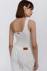 Top tejido de un hombro color blanco, con detalle de hebilla de metal en el tirante.
