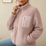 Campera de corderito color blanco, con cuello alto, cierre frontal completo y un bolsillo en el pecho con cierre.