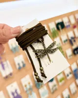 Choker de tiento de gamuza color marrón con dije central de libélula en metal envejecido y terminales con cuentas metálicas.