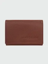 Billetera compacta Longchamp modelo Le Foulonné, confeccionada en cuero granulado color marrón, con logo de la marca grabado en el frente.