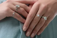 Anillo de plata con ópalo blanco ovalado en el centro, flanqueado por pequeños detalles de circonias en el aro.