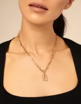 Dije con forma de letra A, elaborado artesanalmente en metal bañado en plata, con diseño inspirado en la estética de clavo característica de la marca.