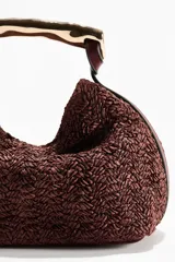 Bolso de mano de textura rugosa color bordó, con asa rígida de metal dorado de diseño ondulado y cierre magnético.