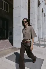 Chaqueta corta de punto color beige, con cuello redondo y manga tres cuartos. Cierre frontal con tres botones forrados a tono.