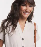 Mono largo color beige, de corte recto, con cuello en V, abotonado delantero, mangas cortas, cintura marcada, bolsillos laterales y bolsillos cargo en las piernas.