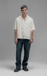 Camisa de manga corta con cuello cubano y cierre frontal de botones, de corte oversize y diseño minimalista.