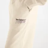 Pantalón de jogging New Balance color beige melange, de corte holgado y pierna ancha. Cuenta con cintura elástica con cordón de ajuste y un pequeño bordado con logo en el muslo izquierdo.