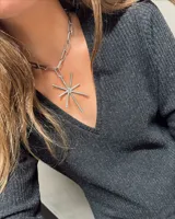 Collar plateado con cadena de eslabones grandes y dije en forma de estrella con puntas. El dije tiene incrustaciones de strass.