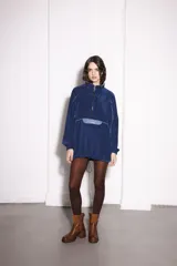 Buzo azul de pana con cierre frontal parcial, cuello alto, bolsillo tipo canguro con solapa y cordón ajustable en el ruedo.