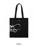 Tote bag negra de lona premium con diseño de graffiti en color blanco estampado en el frente. Cuenta con dos asas largas para llevar al hombro.