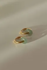 Par de aros tipo argolla dorados de acero quirúrgico, con una piedra natural de color gris translúcido colgando de cada uno.