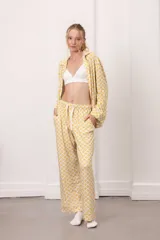 Conjunto de pijama de dos piezas con estampado geométrico en amarillo y blanco. Incluye una camisa de manga larga con cuello y botones frontales, y un pantalón largo con cintura elástica y cordón ajustable.