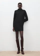 Vestido corto de punto negro con cuello alto y detalle de botones metálicos en el hombro, de mangas largas y corte recto.