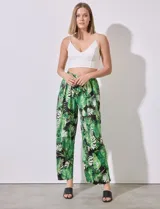 Pantalón largo de seda fría estampada con hojas de palmera en tonos verdes y blancos sobre fondo negro. Tiene pretina ancha elastizada.