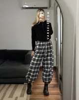 Pantalón estilo balloon de tela escocesa, con cintura elástica y cordón ajustable. Presenta un diseño holgado con puños elásticos en los tobillos.