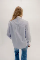 Camisa de manga larga color rosa claro con textura, cuello y puños blancos contrastantes. Los puños tienen tres botones rosados.