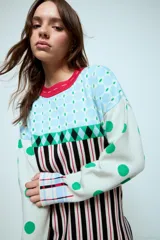 Sweater de punto con diseño geométrico y a rayas, de corte holgado y manga larga. Presenta un patrón combinado de lunares en las mangas, rombos en la parte superior y rayas verticales en el cuerpo.