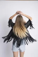 Campera corta de cuero sintético negro, con solapas, mangas 3/4 con tachas y flecos.