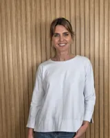Remerón blanco de manga larga con cuello redondo, corte holgado y diseño asimétrico más largo en la parte trasera.