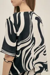 Top de escote redondo y manga corta, con corte asimétrico en la espalda. Confeccionado en lino viscosa, con estampado abstracto en blanco y negro.