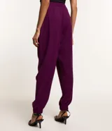 Pantalón jogger de tiro alto confeccionado en crepé color violeta. Presenta pliegues frontales, bolsillos laterales tipo cuchillo y puños elásticos en los tobillos.