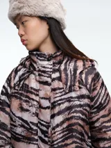 Campera acolchada con estampado animal print tipo tigre en tonos marrones y negros. Presenta cierre frontal, cuello alto, capucha y bolsillos delanteros con solapa.