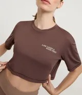 Remera deportiva Get Over de corte cropped y calce suelto, confeccionada en poliamida. Presenta manga corta, escote redondo y estampa frontal con texto en el pecho. Incluye una abertura vertical en la espalda para mayor ventilación.