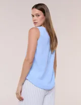 Blusa sin mangas color celeste, de cuello redondo y corte recto, con detalle de botones decorativos en el lateral del ruedo.